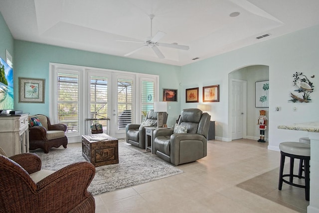 living room featuring french doors, light tile patterned floors, ceiling fan, and a tray ceiling