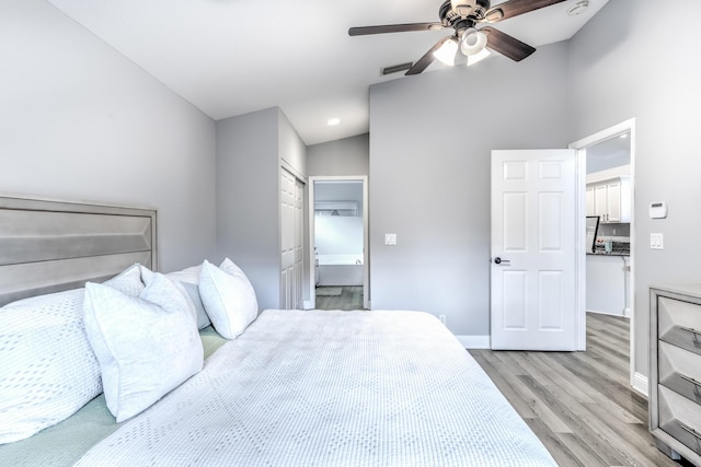 bedroom featuring lofted ceiling, connected bathroom, ceiling fan, and light wood-type flooring