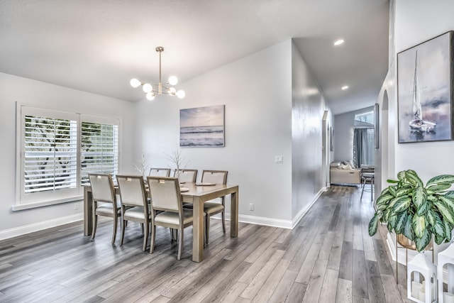 dining room featuring hardwood / wood-style flooring, vaulted ceiling, and a chandelier