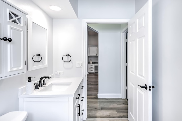 bathroom featuring vanity, wood-type flooring, and toilet