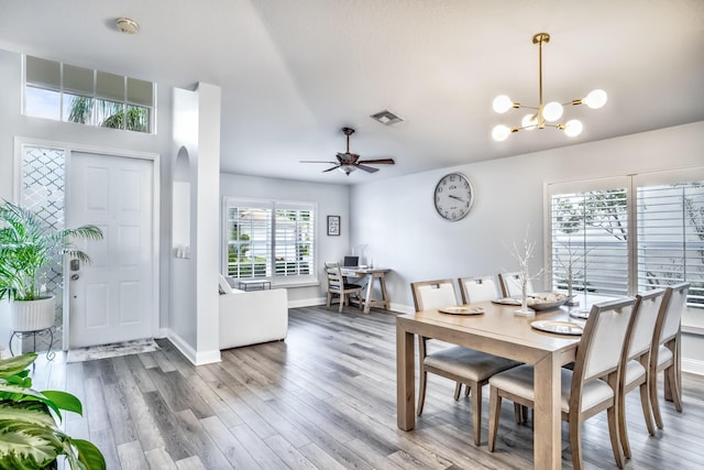 dining area with ceiling fan with notable chandelier and hardwood / wood-style floors