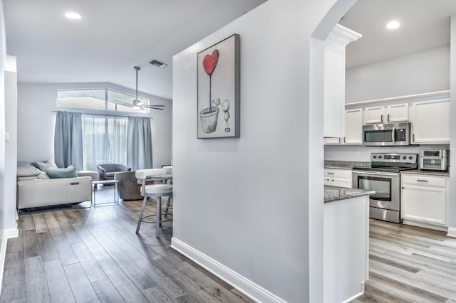 hallway featuring vaulted ceiling and light hardwood / wood-style flooring