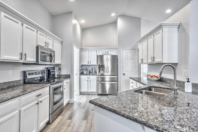 kitchen with white cabinetry, sink, dark stone countertops, stainless steel appliances, and light hardwood / wood-style flooring