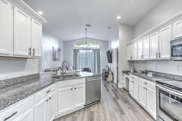 kitchen featuring lofted ceiling, sink, appliances with stainless steel finishes, white cabinetry, and light hardwood / wood-style floors