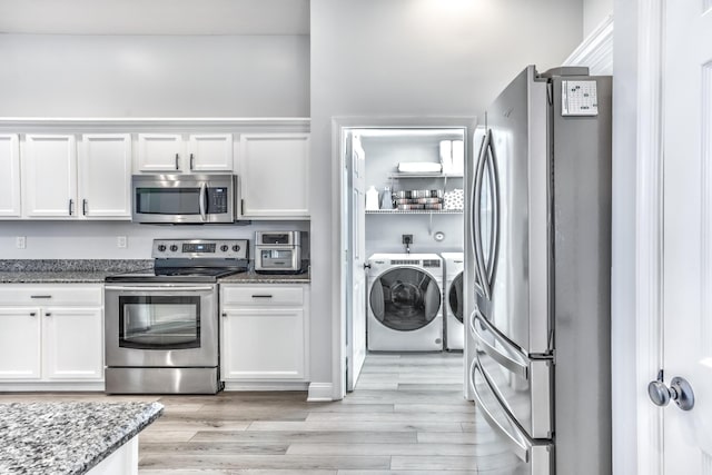 kitchen featuring dark stone countertops, stainless steel appliances, washer and dryer, and white cabinets