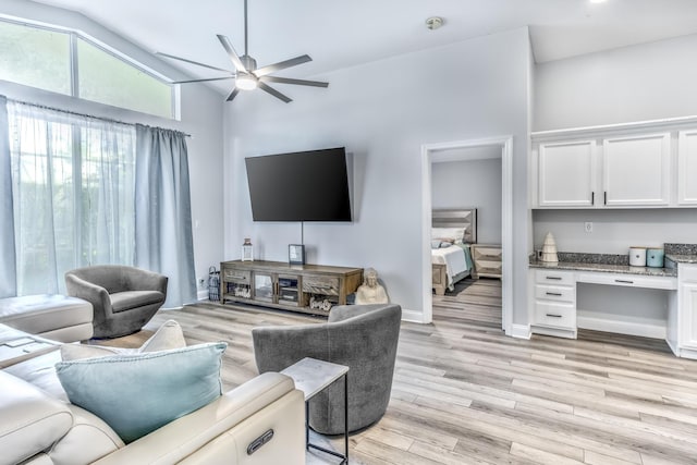 living room featuring vaulted ceiling, built in desk, ceiling fan, and light hardwood / wood-style floors