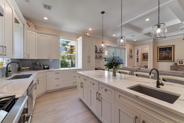 kitchen with crown molding, visible vents, open floor plan, and a sink
