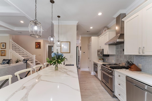 kitchen with wall chimney exhaust hood, appliances with stainless steel finishes, white cabinetry, and crown molding