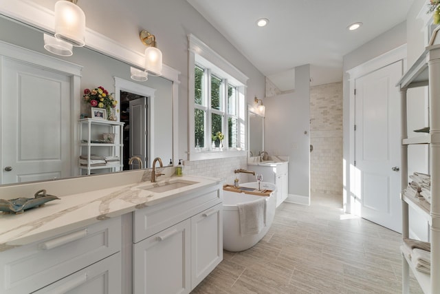 bathroom with recessed lighting, a soaking tub, decorative backsplash, vanity, and a walk in shower