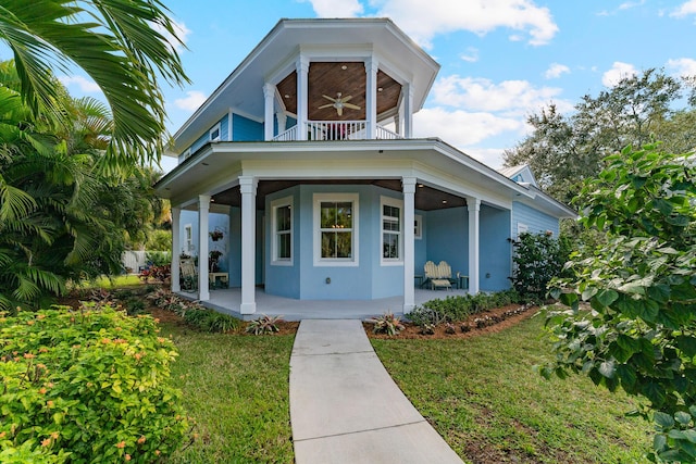 view of front of house with a balcony, ceiling fan, and a front lawn