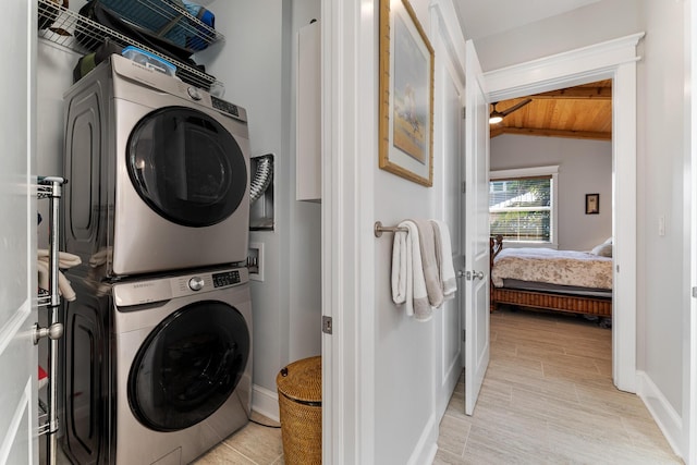 laundry room with laundry area, light wood-style flooring, and stacked washer / drying machine