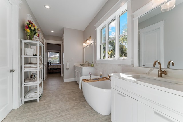 bathroom with vanity, plenty of natural light, wood-type flooring, and a washtub