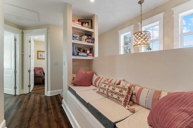 living area featuring plenty of natural light, built in shelves, baseboards, and dark wood finished floors