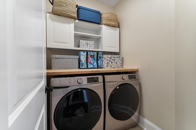 laundry room with washing machine and dryer, cabinet space, and baseboards