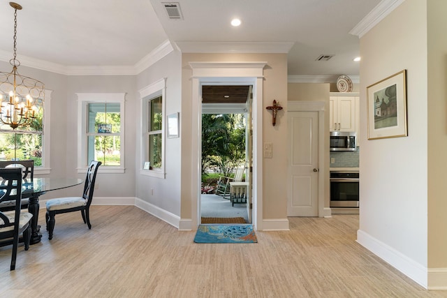 foyer with ornamental molding, light hardwood / wood-style floors, and a notable chandelier