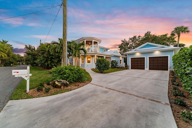 view of front of house with an outbuilding, an attached garage, a balcony, concrete driveway, and a front lawn