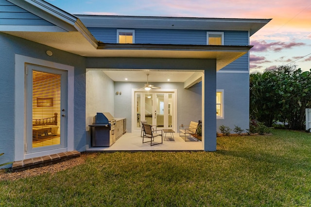 back of property featuring a yard, a ceiling fan, a patio, and stucco siding
