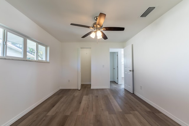 unfurnished bedroom with dark wood-type flooring, ceiling fan, and a closet