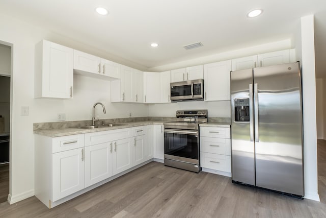 kitchen with white cabinetry, sink, light wood-type flooring, and appliances with stainless steel finishes