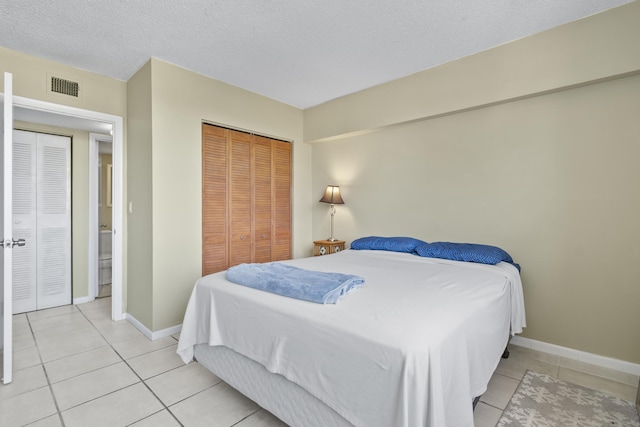 bedroom featuring light tile patterned floors, a textured ceiling, and a closet