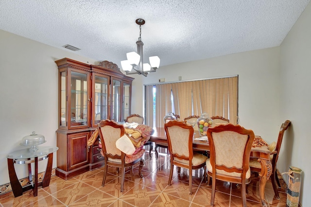 dining room featuring tile patterned flooring, a textured ceiling, and a notable chandelier