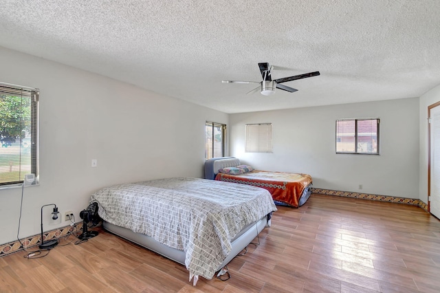 bedroom with hardwood / wood-style flooring, ceiling fan, and a textured ceiling