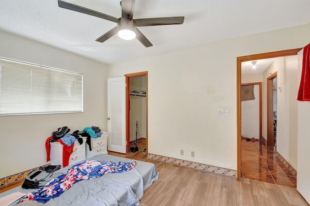 bedroom with ceiling fan, a closet, light hardwood / wood-style flooring, and a textured ceiling