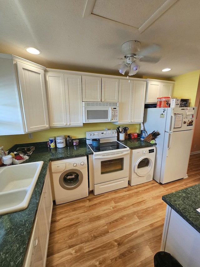 kitchen featuring white appliances, washer / clothes dryer, sink, and light hardwood / wood-style flooring