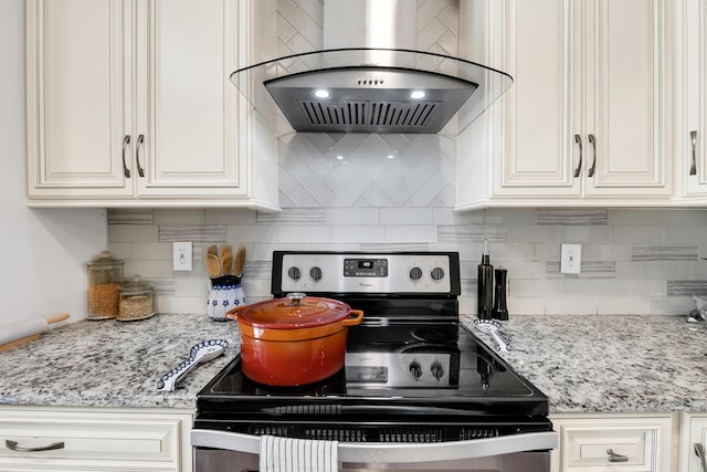 kitchen with light stone counters, stainless steel range with electric stovetop, backsplash, range hood, and white cabinets