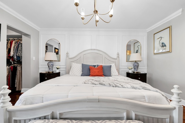 bedroom featuring an inviting chandelier, a walk in closet, crown molding, and dark hardwood / wood-style floors