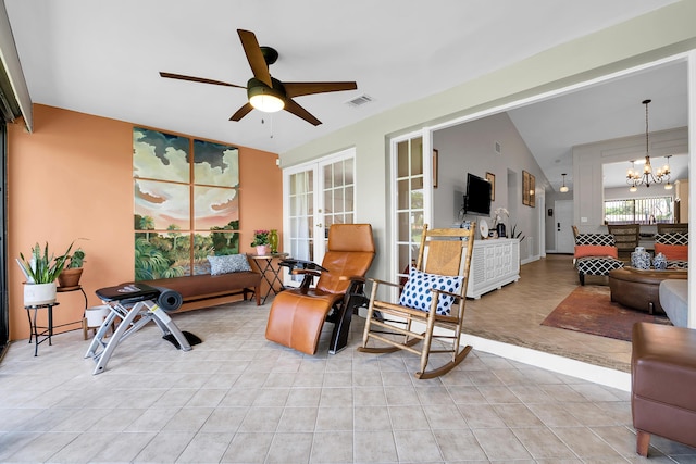 tiled living room featuring vaulted ceiling, ceiling fan with notable chandelier, and french doors