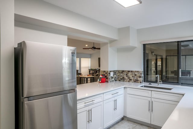 kitchen with sink, tasteful backsplash, stainless steel refrigerator, ceiling fan, and white cabinets