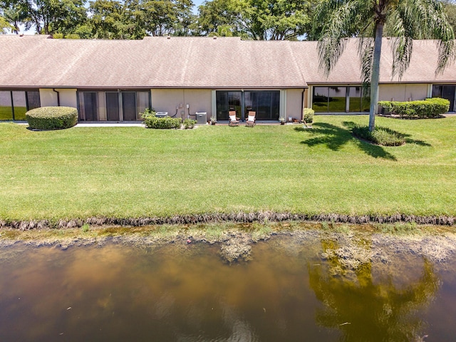 back of property with a yard and a water view