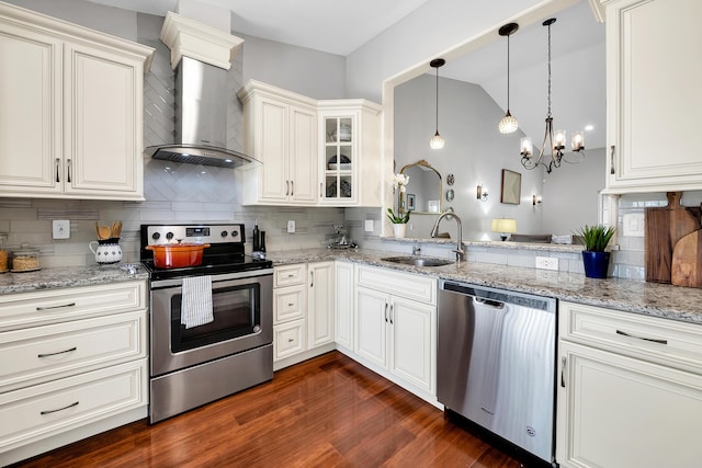 kitchen with appliances with stainless steel finishes, dark hardwood / wood-style floors, sink, hanging light fixtures, and wall chimney exhaust hood