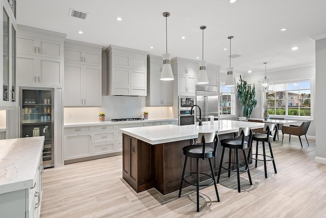 kitchen with tasteful backsplash, visible vents, ornamental molding, built in appliances, and premium range hood