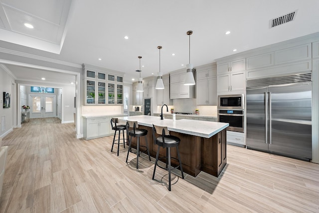 kitchen featuring built in appliances, a breakfast bar, visible vents, french doors, and a large island