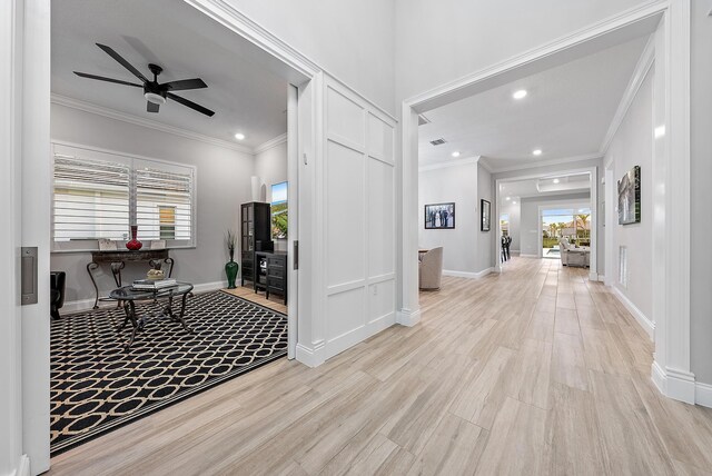 interior space with plenty of natural light, light wood-type flooring, baseboards, and crown molding