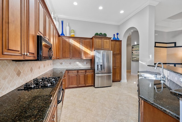 kitchen with ornamental molding, decorative backsplash, dark stone counters, and black appliances