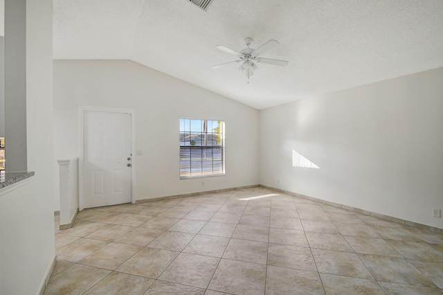 empty room featuring light tile patterned flooring, vaulted ceiling, a textured ceiling, and ceiling fan