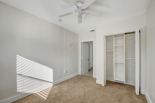 unfurnished bedroom featuring ceiling fan, a closet, light carpet, and a textured ceiling