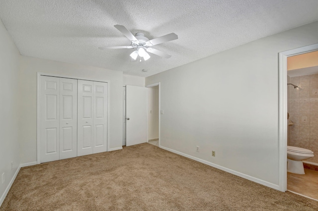 unfurnished bedroom with carpet, ceiling fan, a textured ceiling, ensuite bath, and a closet