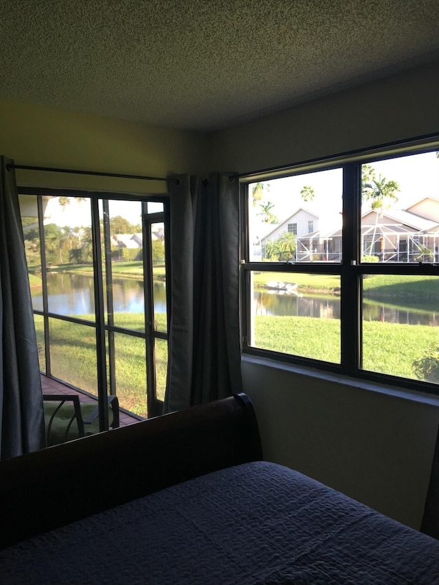 bedroom with a water view and a textured ceiling