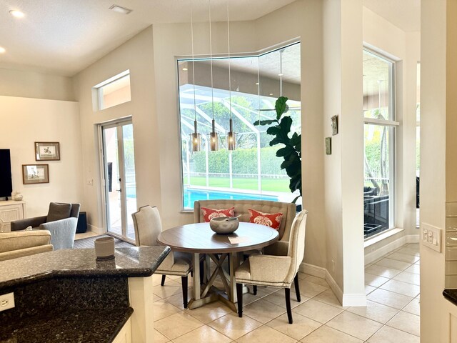 tiled dining space with an inviting chandelier, plenty of natural light, a raised ceiling, and a high ceiling