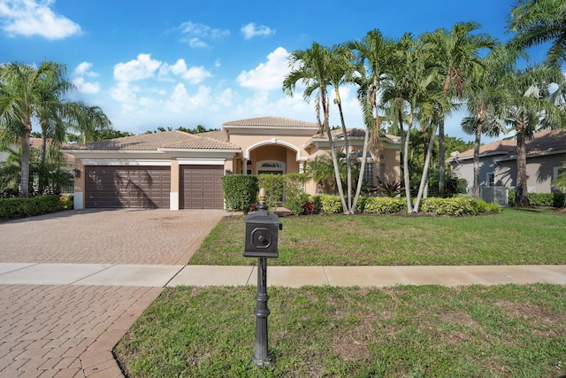 mediterranean / spanish house featuring a garage and a front lawn