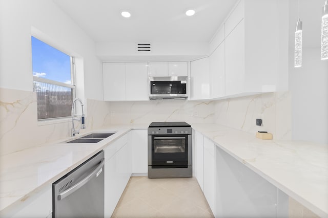 kitchen featuring sink, appliances with stainless steel finishes, white cabinets, pendant lighting, and backsplash