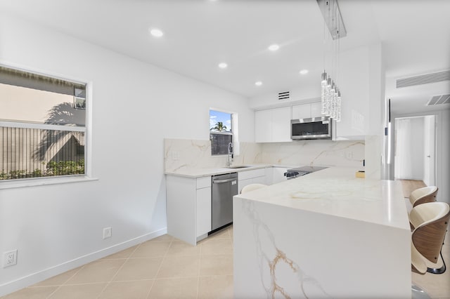 kitchen with white cabinetry, light tile patterned floors, pendant lighting, stainless steel appliances, and decorative backsplash