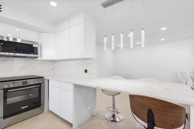 kitchen featuring a breakfast bar, appliances with stainless steel finishes, hanging light fixtures, white cabinets, and kitchen peninsula