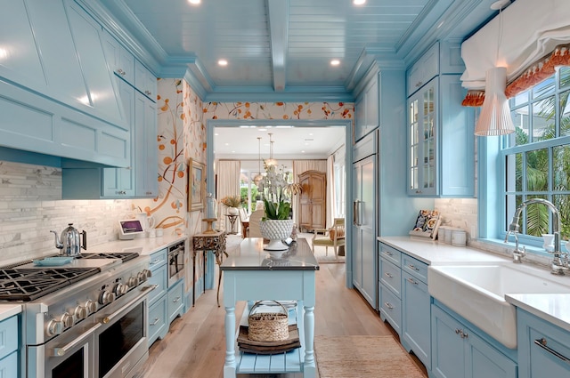 kitchen featuring high quality appliances, crown molding, sink, and decorative light fixtures