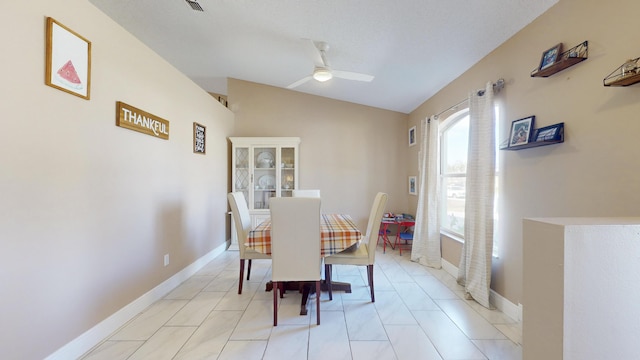 dining room featuring lofted ceiling, ceiling fan, and light tile patterned flooring