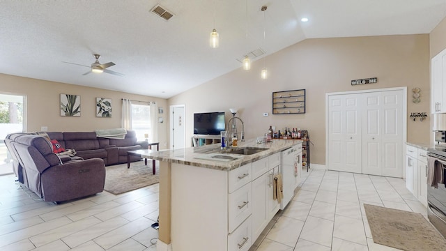 kitchen featuring sink, light stone counters, dishwasher, a kitchen island with sink, and white cabinets